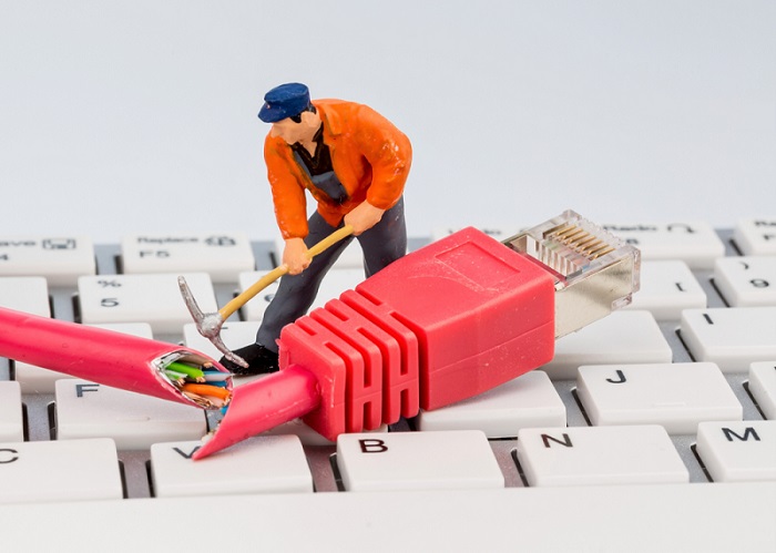 internet problems A little figurine of a man with a pick, cutting down the internet cable.