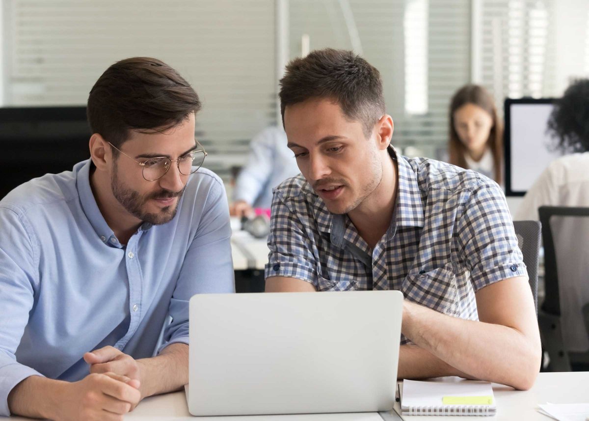 Focused serious male coworkers talking working together on compu