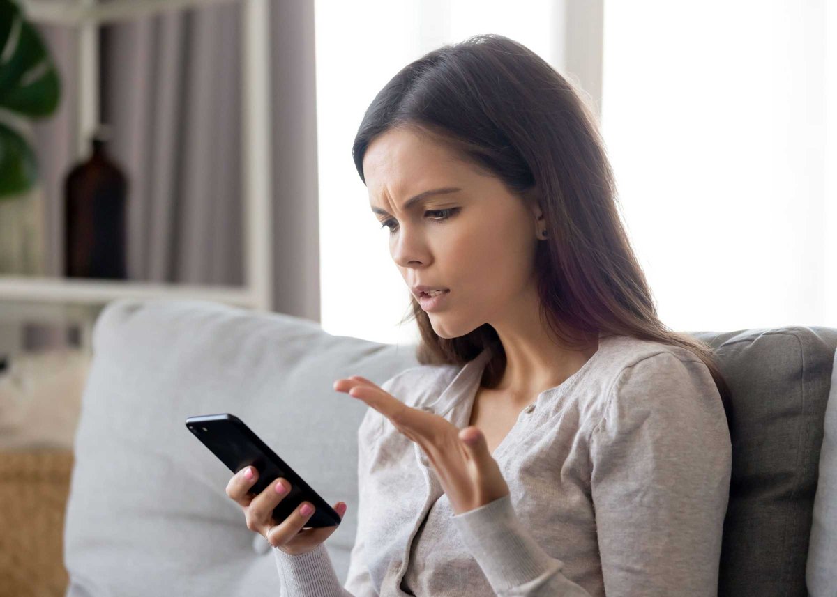 Upset young woman having problem with mobile phone, reading bad news