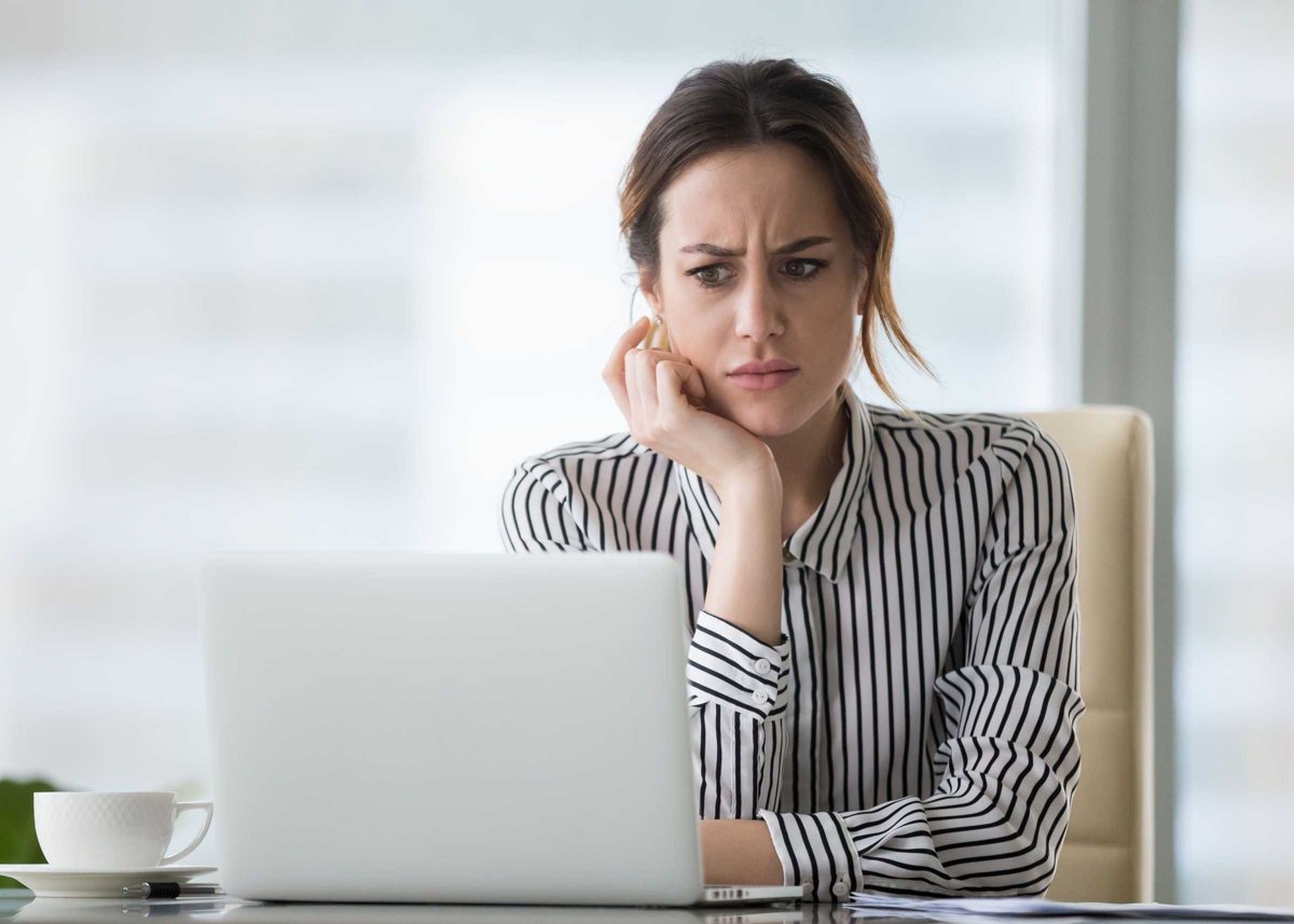 Confused businesswoman annoyed by online problem looking at laptop