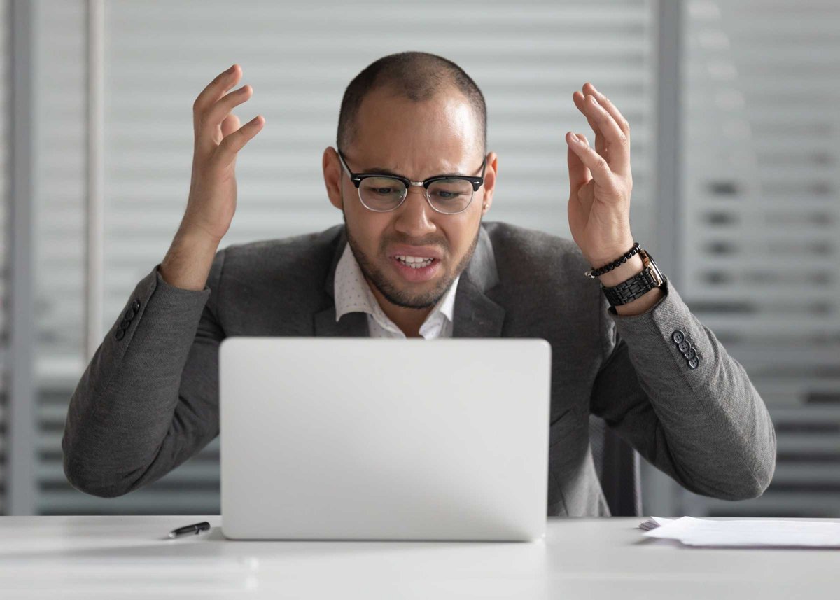 Angry african business man using laptop mad about computer problem