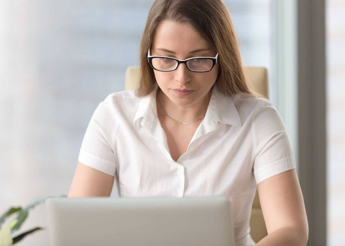 Serious worried businesswoman working on laptop, looking at scre