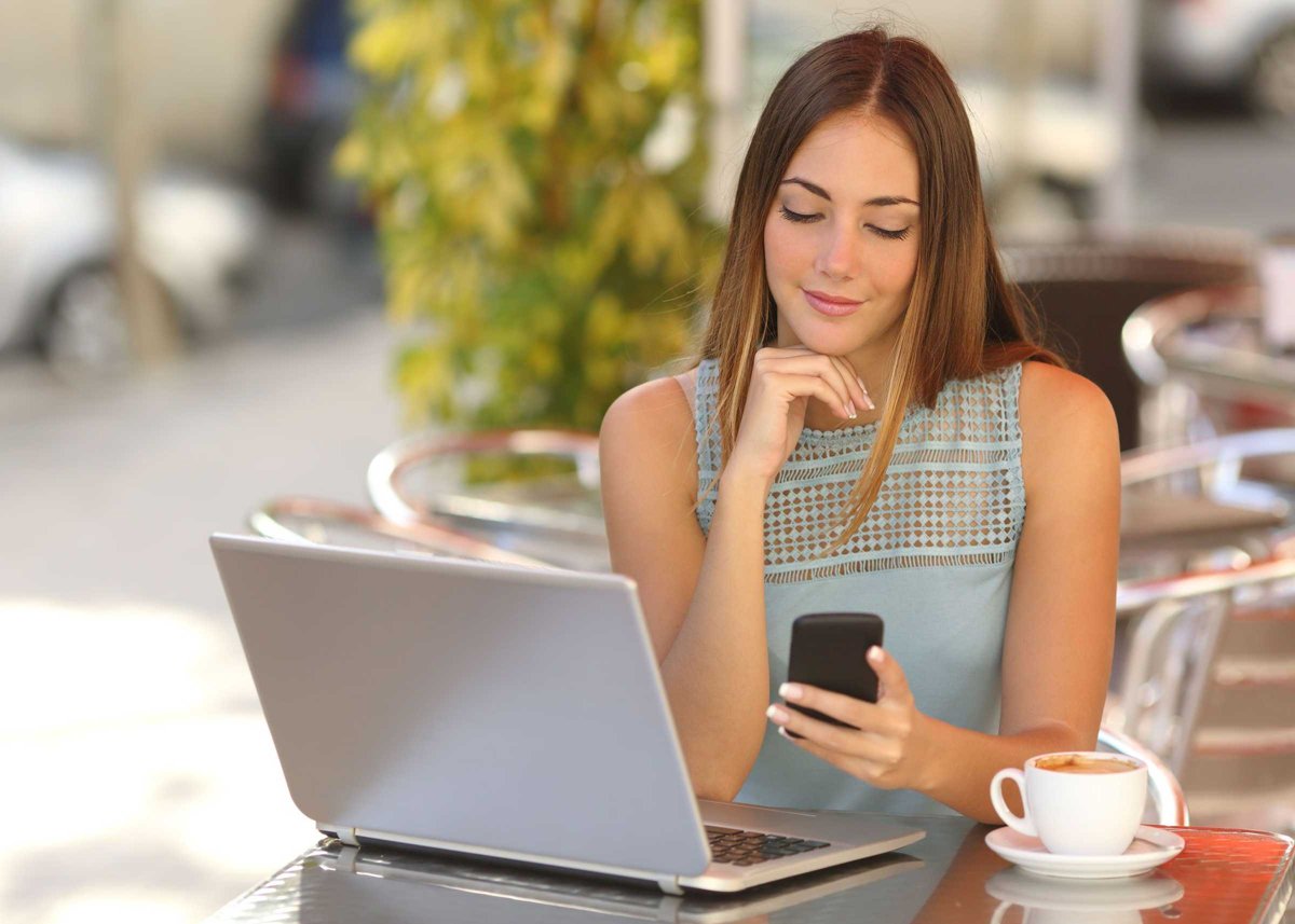 Self employed woman working with her phone and laptop in a restaurant