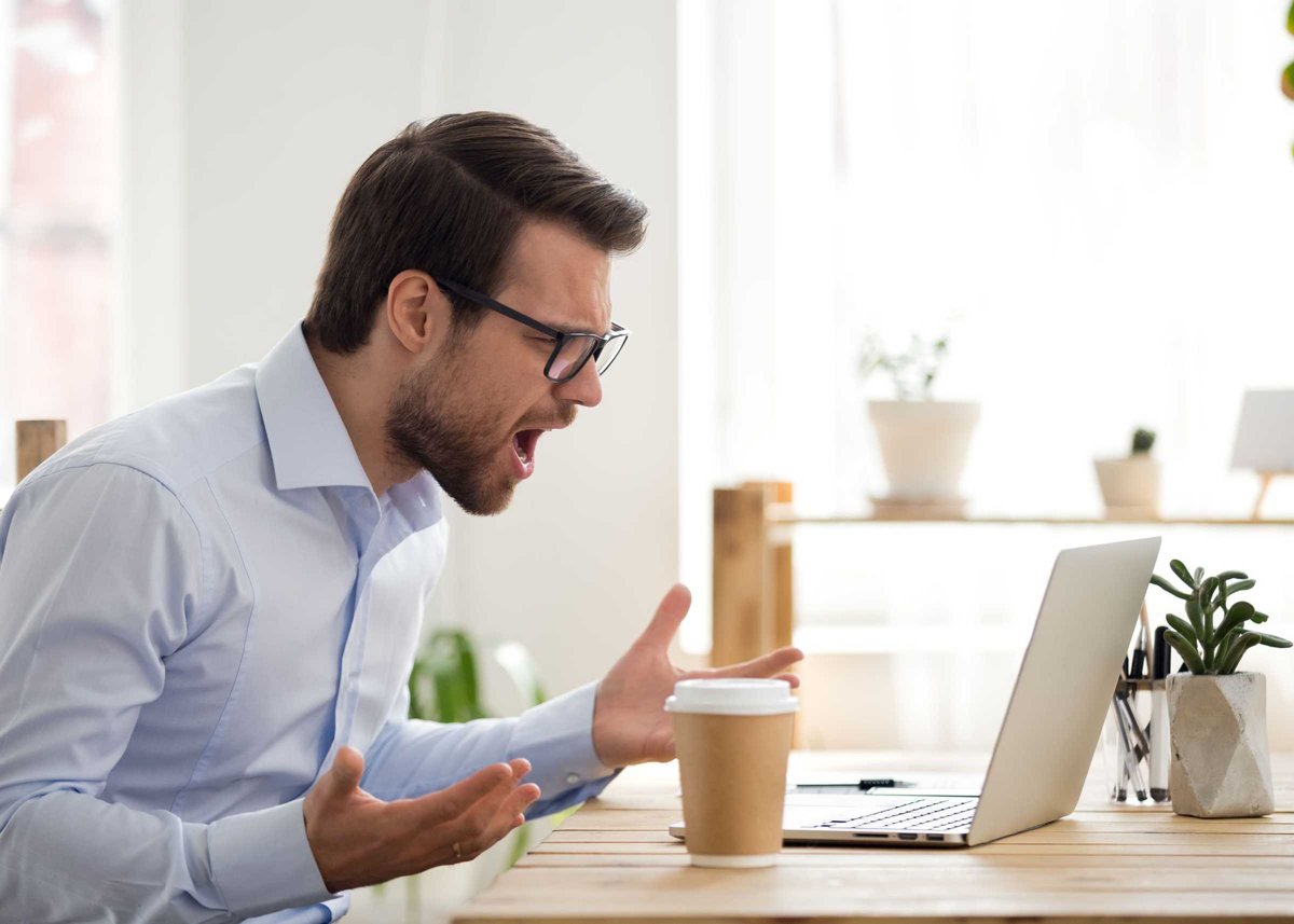 Furious male employee have laptop problems while working