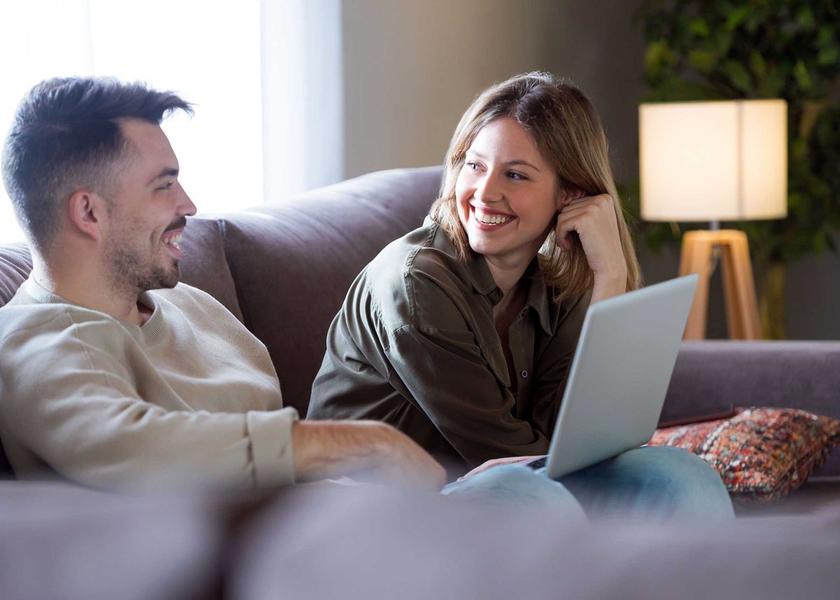 Beautiful young smiling couple using their laptop at home.