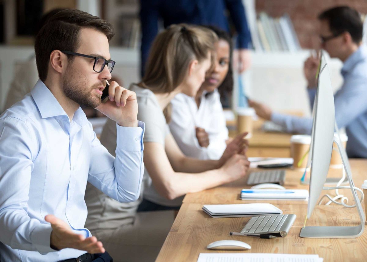 Angry male worker talk on phone solving business problems