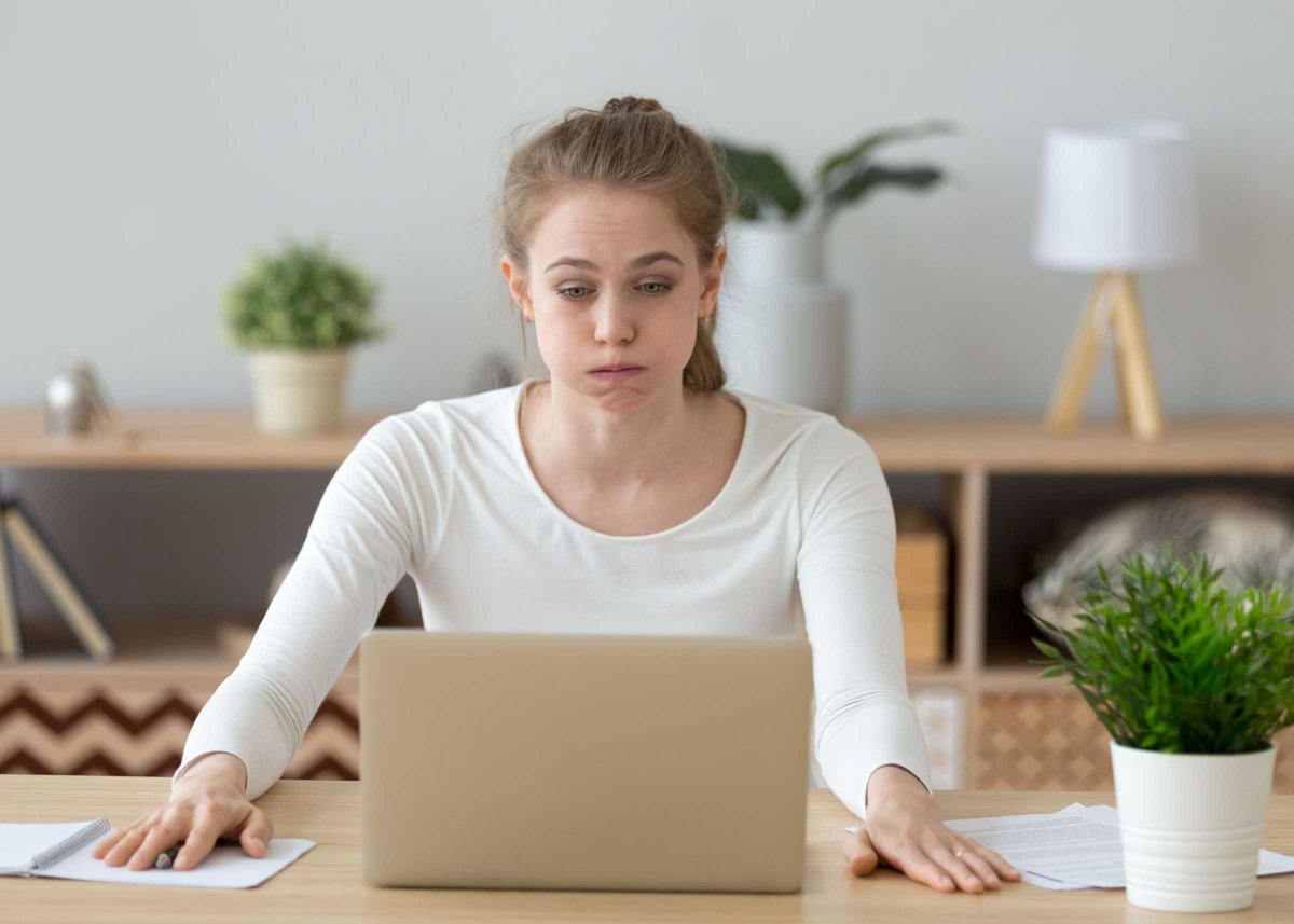 Confused woman looking at laptop screen, doing difficult computer work
