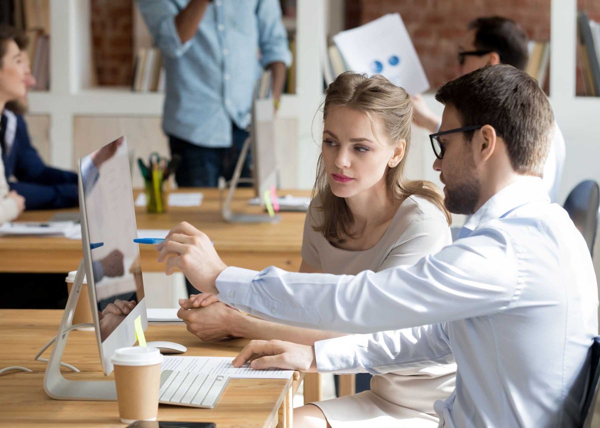 Executive manager teaching employee showing online project pointing on computer