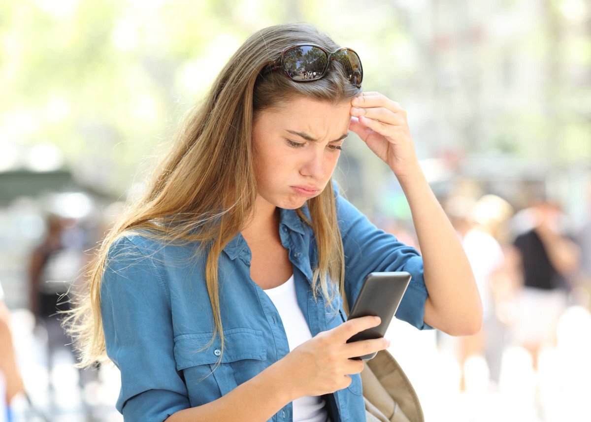 Frustrated woman reading phone content in the street