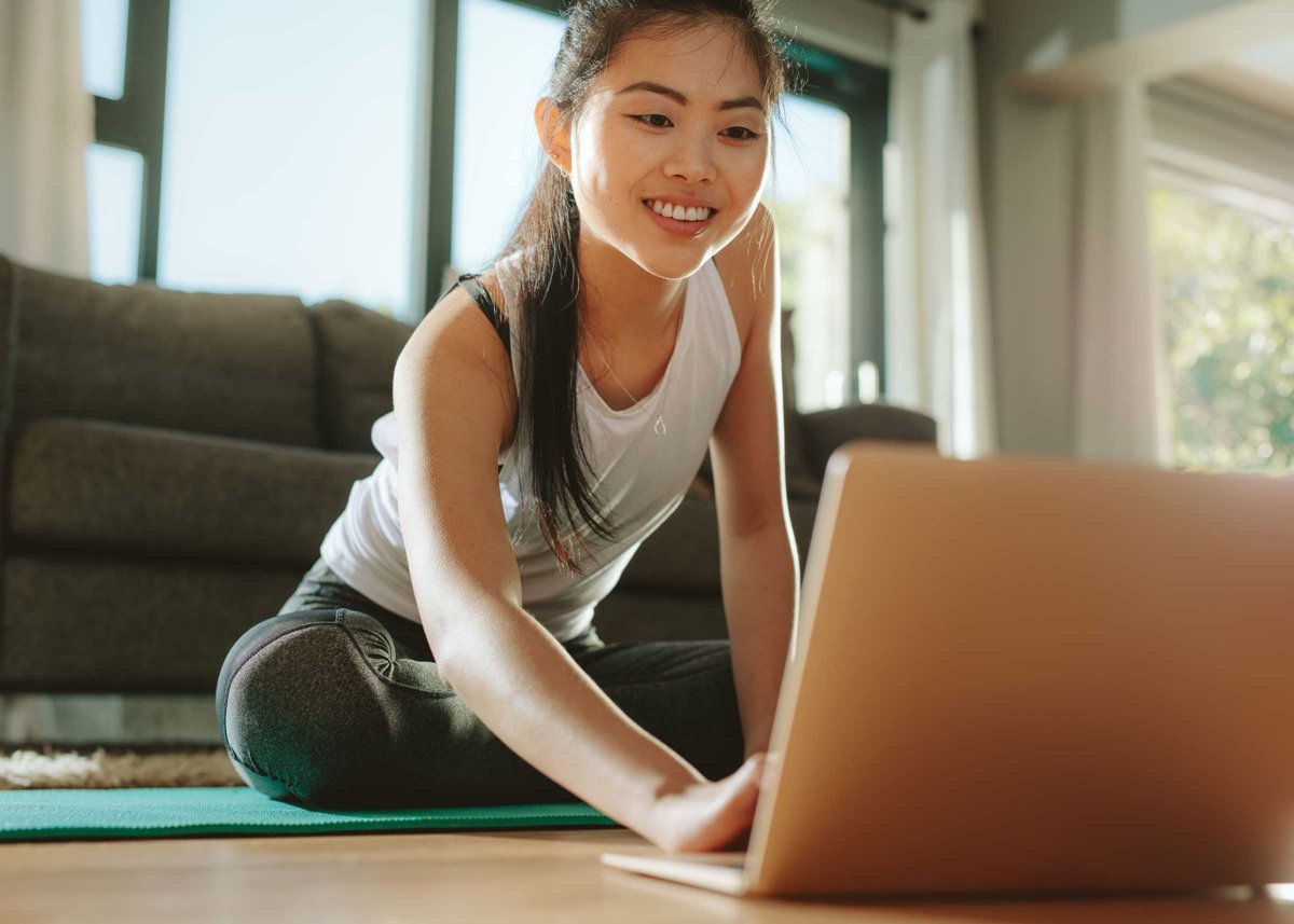 Woman using laptop while exercising at home
