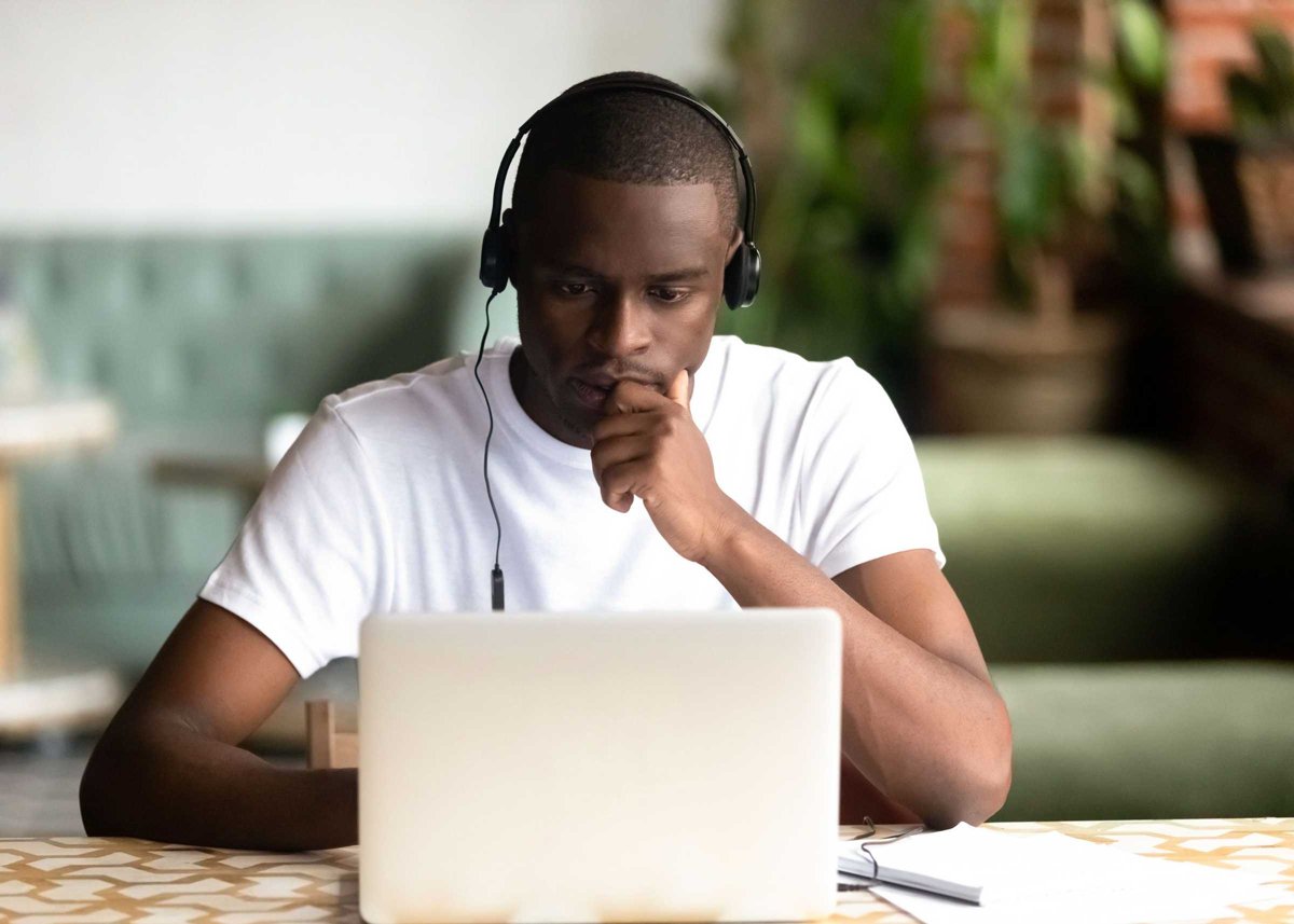 Focused African American man wear headphones, using laptop