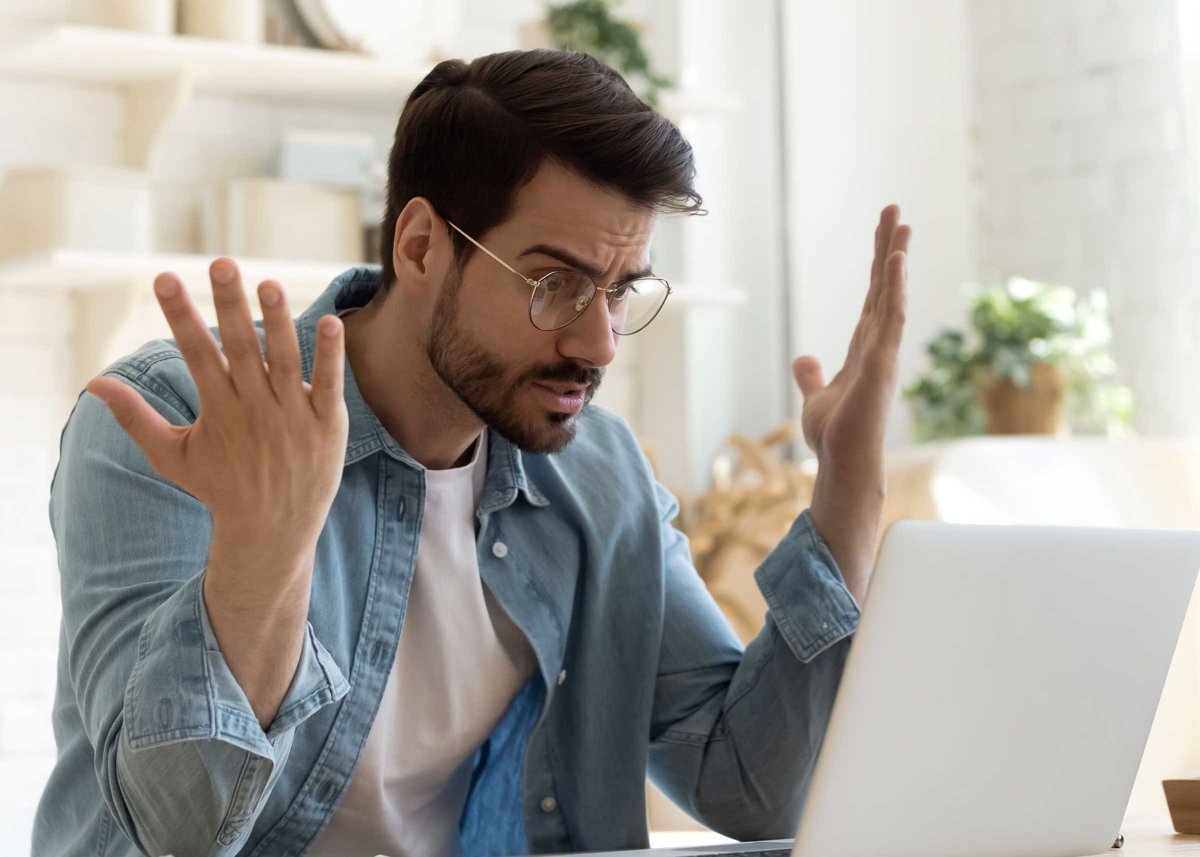 Angry frustrated young man furious about laptop computer malfunction