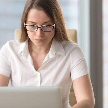 Serious worried businesswoman working on laptop, looking at scre