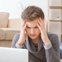 Depressed teenager using laptop on floor in room