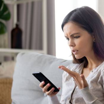 Upset young woman having problem with mobile phone, reading bad news