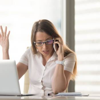 Disgruntled angry businesswoman arguing on cell phone sitting at