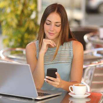 Self employed woman working with her phone and laptop in a restaurant