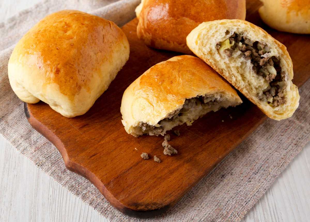 Home-baked Beef Russian Bierocks on a rustic wooden board on a white wooden background, low angle view.