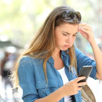 Frustrated woman reading phone content in the street