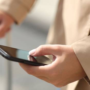 Traveler woman hand consulting a smartphone and holding a suit case