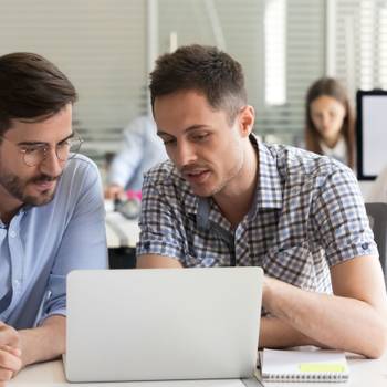 Focused serious male coworkers talking working together on compu