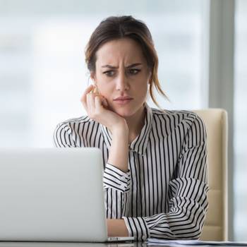 Confused businesswoman annoyed by online problem looking at laptop