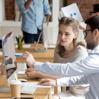 Executive manager teaching employee showing online project pointing on computer