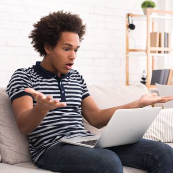 Shocked teen guy having problem in laptop