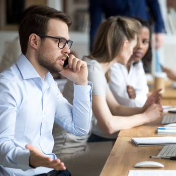 Angry male worker talk on phone solving business problems