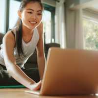 Woman using laptop while exercising at home
