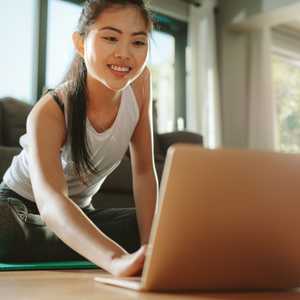 Woman using laptop while exercising at home