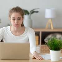 Confused woman looking at laptop screen, doing difficult computer work
