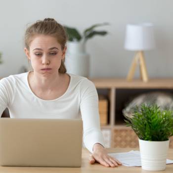 Confused woman looking at laptop screen, doing difficult computer work